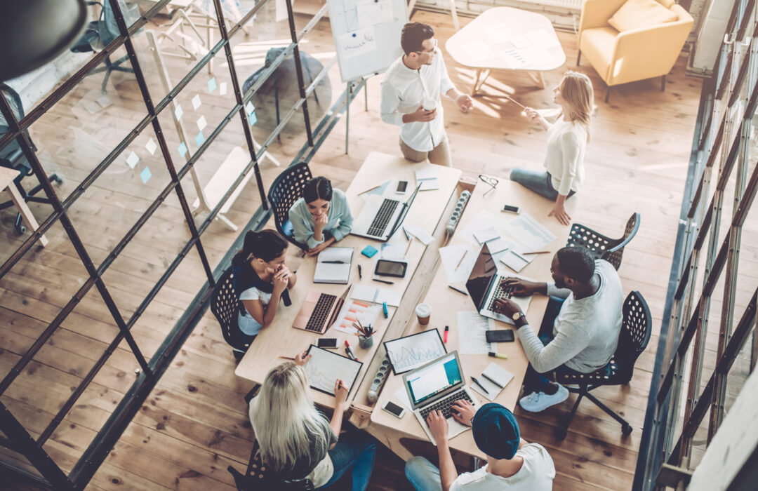 Top view of multiracial young creative people in modern office. Group of young business people are working together with laptop, tablet, smart phone, notebook. Successful hipster team in coworking. Freelancers.